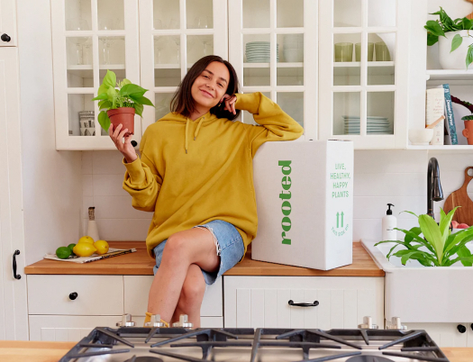 Woman sitting on kitchen counter next to rooted shipping box